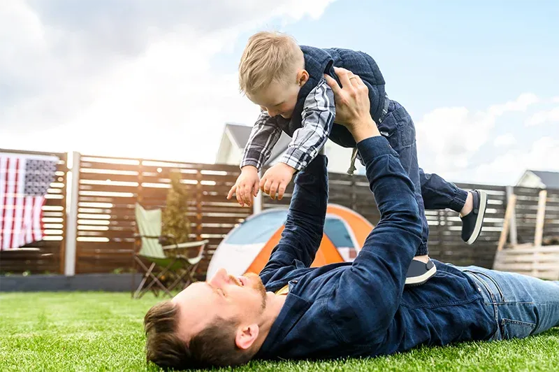 father and son playing outside in backyard
