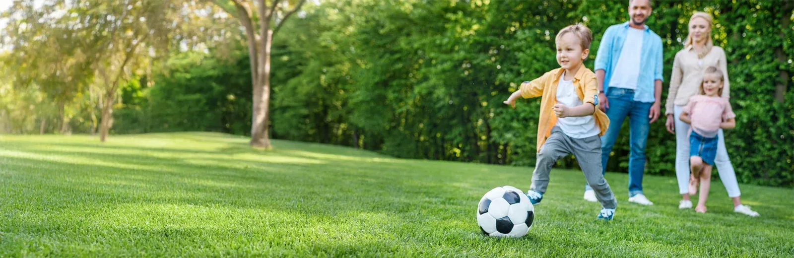 family playing soccer outside on green lawn