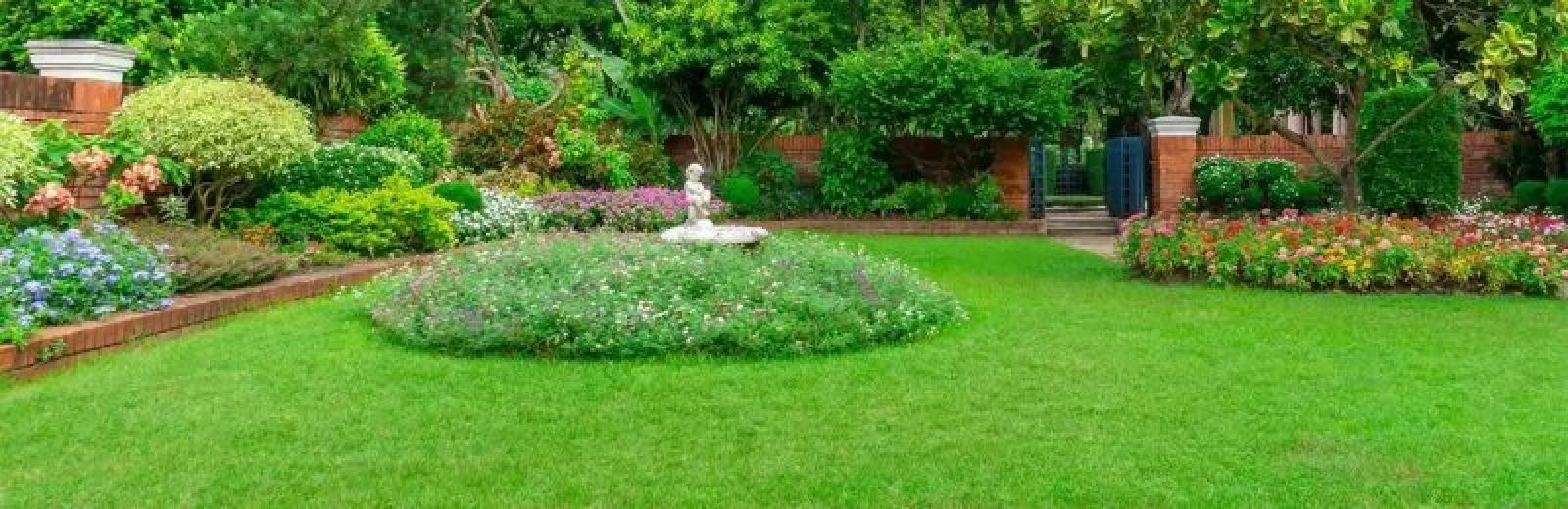 green grass with flower beds with a statue